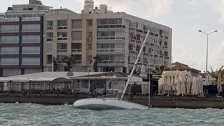 Çeşme'de fırtına nedeniyle yan yatan tekne karaya vurdu